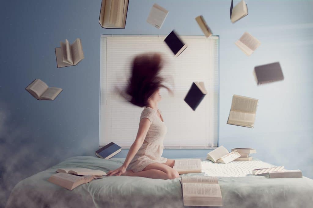 side gig - woman on bed with books flying in the air